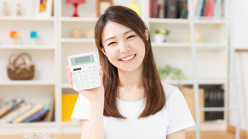 電卓を手に、品川で歯列矯正を安い費用で始められることを伝える女性]